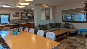 Une cuisine moderne avec un coin repas, une grande fenêtre et un salon comprenant un canapé et des fauteuils.