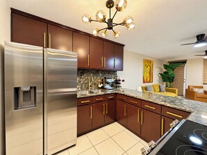 A modern kitchen with stainless steel appliances, wooden cabinets, and a granite countertop. - Rincon Ocean Views and Sunsets, 2 King Beds, Pool, Beach Across the Road (Rincón)