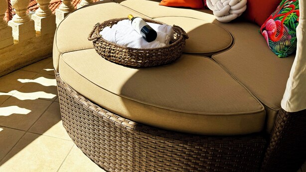 A covered outdoor seating area with a wicker sofa, cushions, and a bottle of wine. - Rincon Ocean Luxe - Le Paradis Royal (Rincón)
