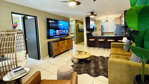 A modern living room with a TV, seating, a dining area, and a kitchen. - Rincon Ocean Luxe - Le Paradis Royal (Rincón)