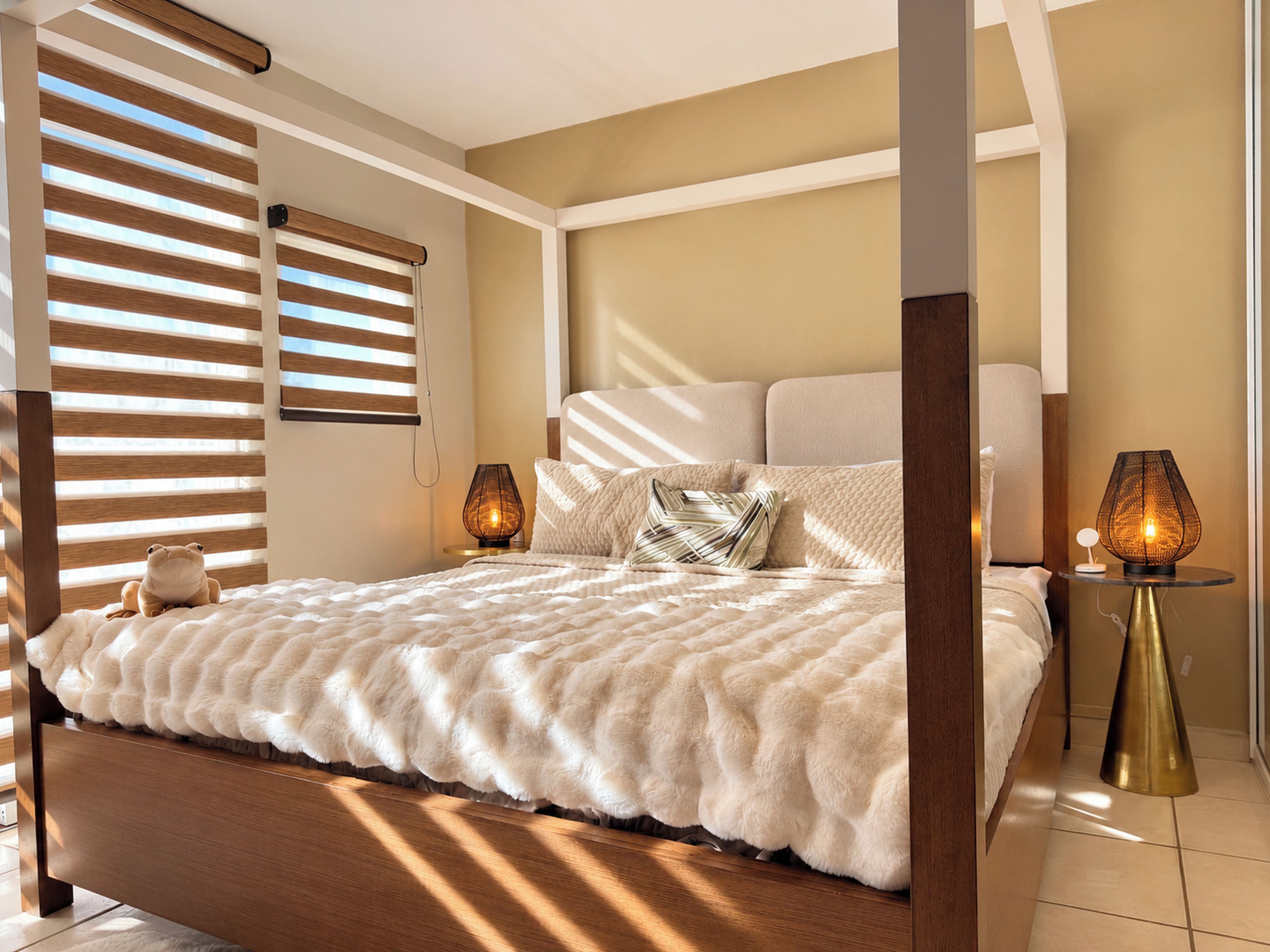 A modern bedroom with a large bed, wooden headboard, and two bedside lamps.