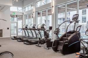 A gym with treadmills, elliptical machines, and a stationary bike, large windows, and a view of the outside. - Austin Exquisite 1BD 1BA 2nd Street District Apartment (Austin)