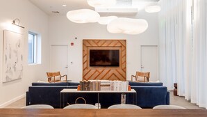 A modern conference room with a wooden accent wall, a large flat-screen TV, and a central table with books.