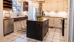 A modern kitchen with white cabinetry, a central island, stainless steel appliances, and a hanging light fixture.