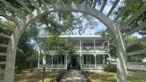 A two-story house with a porch, a front door, and a mailbox.