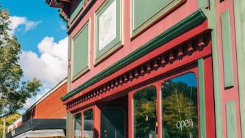 Edificio rosso e verde con ampie finestre e un cartello con su scritto 'aperto'.