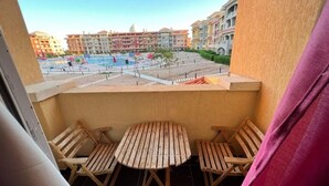 A balcony with two wooden chairs and a small table, overlooking a swimming pool and buildings. - Porto Sharm Hotel & Resort  (Sharm El Sheikh)