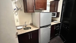 A compact kitchen with dark cabinets, a white refrigerator, a microwave, and a sink. - Porto Sharm Hotel & Resort  (Sharm El Sheikh)