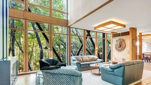 A spacious living area with large windows, a fireplace, and a stone wall with a lion sculpture.