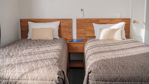A hotel room with two beds, wooden headboards, bedside tables, and wall-mounted light fixtures. - Samhil Motor Lodge (Christchurch)