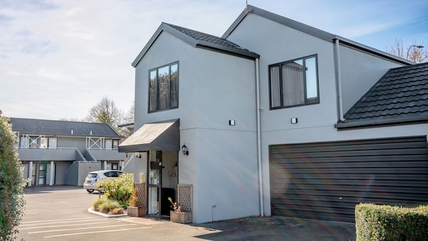A modern two-story building with a garage, a covered entrance, and a parking lot. - Samhil Motor Lodge (Christchurch)