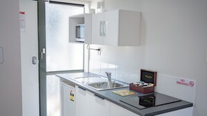 A small kitchenette with a sink, microwave, and cabinets. - Samhil Motor Lodge (Christchurch)