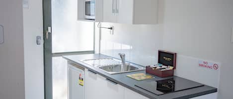 Una kitchenette pequeña con pileta, microondas y placares.