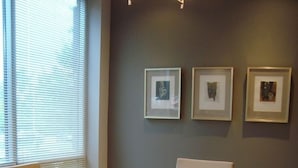 A conference room with a wooden table, four chairs, and three framed pictures on the wall. - Samhil Motor Lodge (Christchurch)