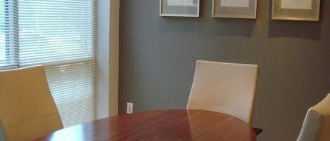 A conference room with a wooden table, four chairs, and three framed pictures on the wall.