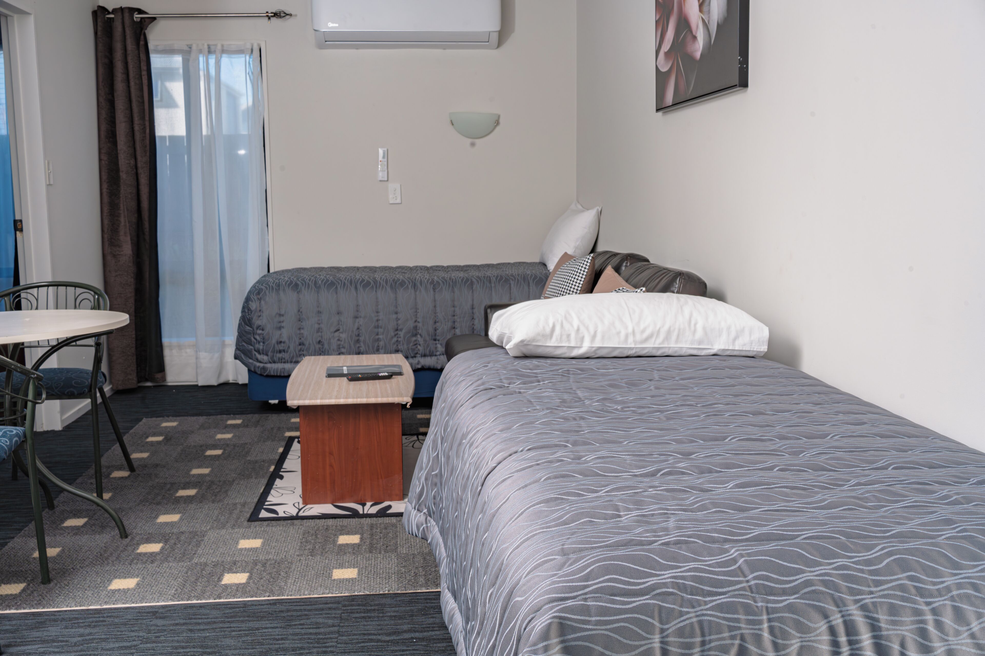 A small, neatly arranged bedroom with two beds, a desk, and a chair.