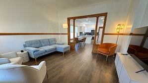 A modern living room with a sofa, armchairs, a coffee table, and a dining area with chairs.