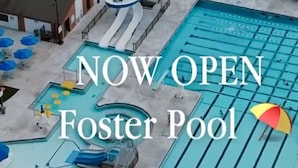 An aerial view of a Foster Pool with a water slide, lounge chairs, and umbrellas.