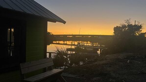 A rustic cabin with a wooden bench and a view of a sunset over a calm body of water. - Nauti Hookers, deep water access in Steinhatchee with a boat slip, cold AC, WiFi (Steinhatchee)