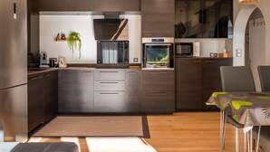 A modern kitchen with dark cabinetry, a built-in oven, a microwave, and a window with a view.