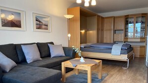 A compact living space with a sofa, a bed, a small table, and a cabinet.