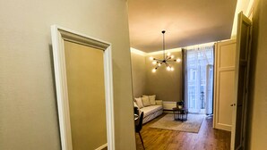 A hallway with a wooden floor, a white door frame, and a ceiling light fixture. - CITY CENTER 2! A Cozy and Modern 2BR in the city center near New York Cafe! (Budapest)