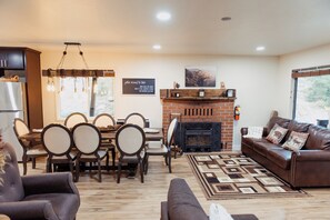 A cozy living room with a fireplace, dining area, and comfortable seating. - Spacious 6-Bedroom Tahoe Cabin, 9 minutes to Sierra Ski Resort! Mountain Views (Twin Bridges)