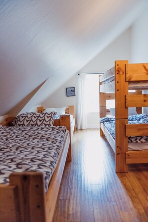 A dormitory room with bunk beds, a wooden floor, and a sloped ceiling. - Spacious 6-Bedroom Tahoe Cabin, 9 minutes to Sierra Ski Resort! Mountain Views (Twin Bridges)