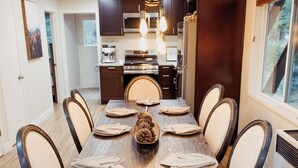 Une salle à manger avec une table en bois, huit chaises et un lustre.