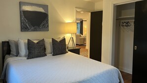 Un dormitorio con cama, lámpara, trípode y puerta que da a otra habitación.