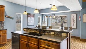A kitchen with a large island, wooden cabinets, a built-in dishwasher, and pendant lighting. - Family-Friendly Lake Retreat, Cmty Firepits, Playground and Hot Tub, Free SDC Tickets & more! (Branson)