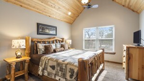 A bedroom with a wooden ceiling, a bed with a quilt, a nightstand with a lamp, a dresser, and a window with blinds. - Family-Friendly Lake Retreat, Cmty Firepits, Playground and Hot Tub, Free SDC Tickets & more! (Branson)