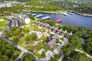 Vista aerea di una zona residenziale sul lago, con case, un porto turistico e un grande edificio con tetto verde.