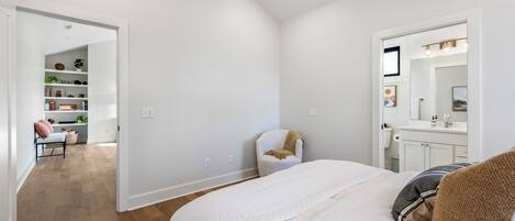 Quarto com cama, cadeira, escrivaninha e estante.