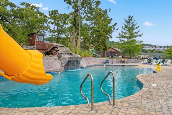 A pool with a slide, a rocky waterfall feature, and a view of a town in the background. - Scenic Table Rock Shoreline w/ Access, Free Daily Tickets & Shared Amenities (Branson)