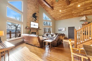 A spacious living room with a fireplace, leather furniture, and large windows offering views of the outdoors.