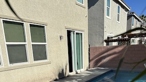 Une piscine située à côté d’un bâtiment dont la façade est en briques et qui est dotée d’une porte-fenêtre coulissante.