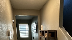 Un couloir doté d’un plancher en bois, d’une bibliothèque intégrée et d’une porte donnant sur une autre pièce.