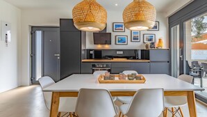 A modern kitchen with dark cabinets, a central island, and a dining area with a white table and chairs. - Beautiful home in Fazana (Fazana)