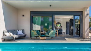 A modern outdoor pool area with a sofa and chairs, a dining table, and a view into the house. - Beautiful home in Fazana (Fazana)