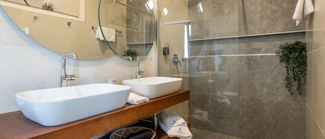 A modern bathroom with two sinks, a glass shower enclosure, and a wooden vanity.