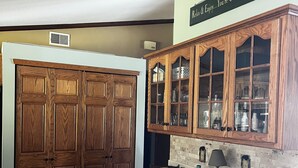 A kitchen with wooden cabinets, a countertop, and a sign above stating "Relax & Enjoy...You're On Cabin Time Now." - Cozy cottage on Bearskin Lake! (Harshaw)