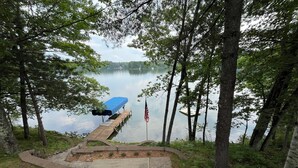 A dock with a blue canopy and an American flag, surrounded by trees and leading to a lake. - Cozy cottage on Bearskin Lake! (Harshaw)