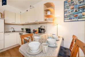 A compact kitchen with white cabinets, a coffee maker, and a dining area with a table set for two.