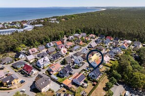 An aerial view of a residential area with houses, roads, and a forested area in the background.