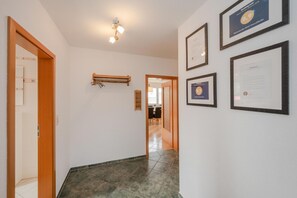 Ein Korridor mit gerahmten Zertifikaten an der Wand, einem hölzernen Türrahmen und einer Deckenleuchte.