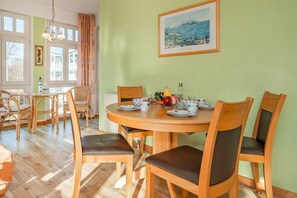 Ein Essbereich mit einem runden Tisch, sechs Stühlen und einem Bild an der Wand.