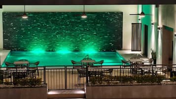 A rooftop pool area with a view of the cityscape, surrounded by seating and a railing.