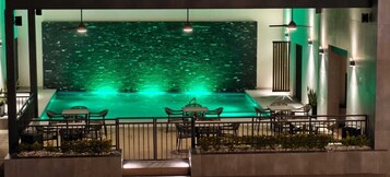 Una piscina en la azotea con vistas a la ciudad, rodeada de asientos y barandilla.