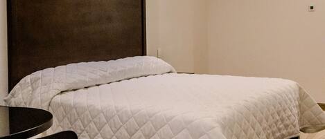 A bedroom with a bed, a chair, a table, and a ceiling fan.